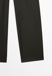 Zwarte broek plat gelegd op een witte achtergrond, die hun gladde textuur en rechte pijpontwerp toont. Geen zichtbare merktekens.