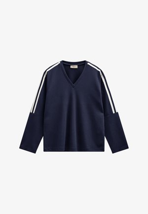 Marineblauwe V-hals trui met lange mouwen, voorzien van witte strepen langs de schouders. Gemaakt van zachte stof met een ontspannen pasvorm.
