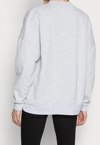 Světlé šedé mikina se kulatým výstřihem, spadlými rameny a žebrovanými manžetami. Nabízí pohodlný střih a měkkou, strukturovanou tkaninu.