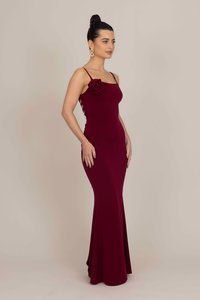 Bordo, uska, bezručna haljina s božurićem sa strane, teksturirana tkanina i lepršavi rub, stvarajući elegantnu siluetu.