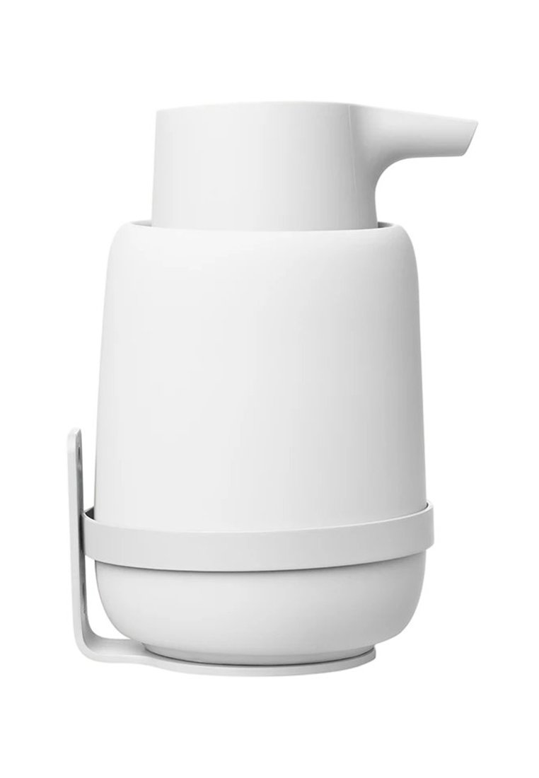 Biały ceramiczny dzbanek o zaokrąglonym korpusie, płaskim dnie i skośnym wylewie. Posiada wymienną, okrągłą podstawę oraz dopasowaną elegancką rączkę.