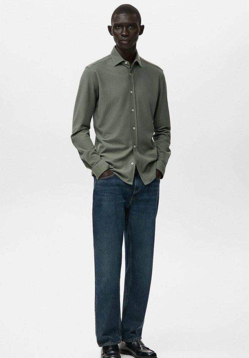 Langærmet, olivengrøn skjorte med button-down krave, parret med blå jeans og sorte sko. Glat stof, afslappet design, tætsiddende form.