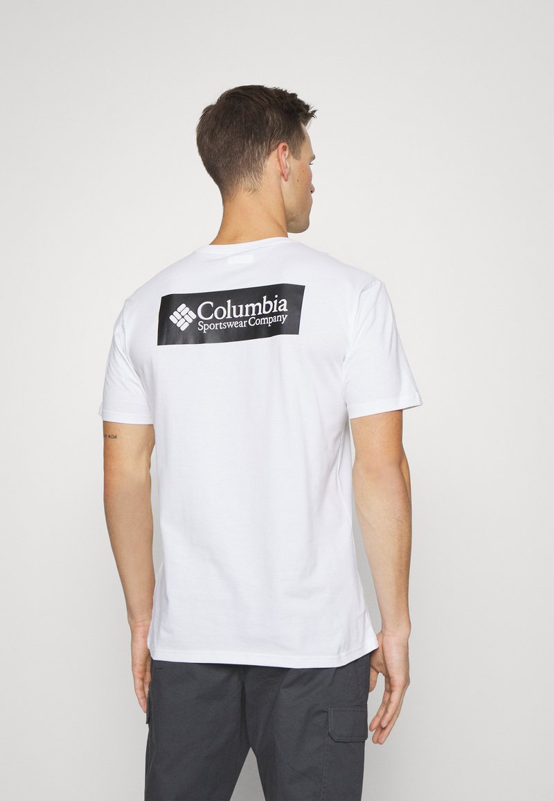 Hvit T-skjorte med korte ermer og en svart rektangulær logo "Columbia Sportswear Company" på baksiden, med rund halsdesign.