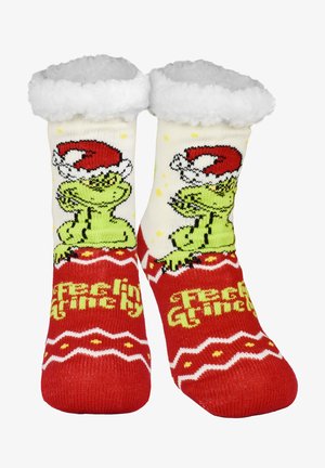 Un paio di calze natalizie rosse e bianche con il Grinch verde che indossa un cappello da Babbo Natale e la scritta "Feeling Grinchy" in giallo.