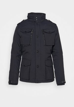 Black insulated jacket with zippered and flap pockets, high collar, button closure, and ribbed cuffs. Smooth texture and tailored fit.