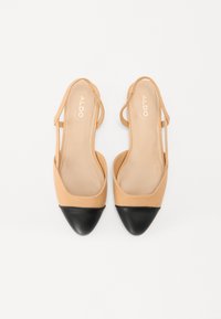 Beige nahkased sussid, millel on terav must varvas ja peened elastsed rihmad. Sile tekstuur ja minimalistlik disain.