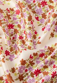 Floral fabric with a cream background, featuring red, pink, and brown flowers, accented with green leaves in a textured weave.