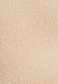 Tissu beige doux avec une texture côtelée, présentant des variations subtiles de couleur et une finition duveteuse. Idéal pour des applications textiles chaudes.