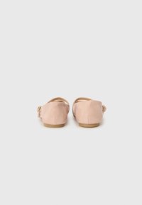 Ljust rosa balettskor med en slät yta, rundad bakdel och elastisk rem för stöd. Mjuk sula med minimalt mönster.
