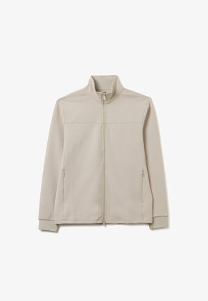 Lichtbeige zip-up jas van zacht materiaal. Voorzien van een hoge kraag, twee zijzakken en ribgebreide manchetten voor een nauwsluitende pasvorm. Glad textuur.