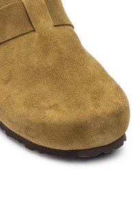 Suede boot with a rounded toe, in a light brown color, featuring a textured, soft finish and a brown rubber sole.