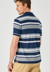 Marine gestreepte poloshirt met grijze en witte accenten, gemaakt van zachte stof. Het heeft een klassieke kraag en korte mouwen met zijsplitten.