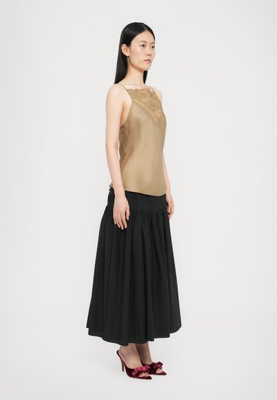 Beige satin top with lace detailing, paired with a black pleated skirt and burgundy velvet heels with bow accents.