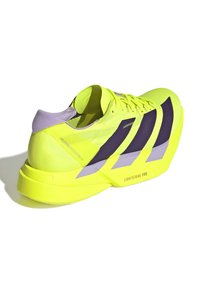 Felgeel sportieve schoen met paarse accenten, getextureerde mesh bovenkant, lichtgewicht ontwerp en een opvallende, uitgesproken zool met het label "LIGHTSTRIKE PRO."