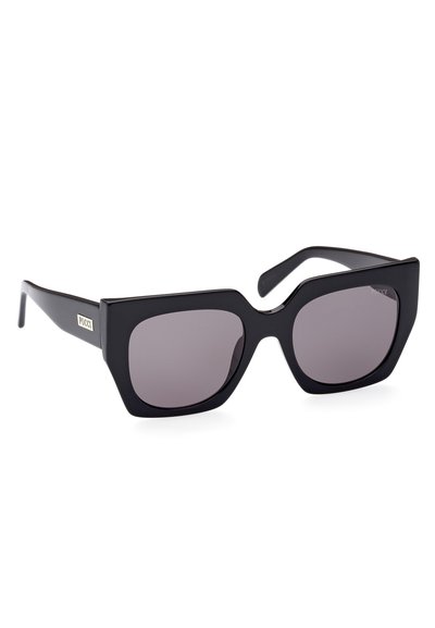 Sorte solbriller med en kraftig, vinklet ramme og mørke gradientlinser. Har et logoaccent på siden i metallisk guld.