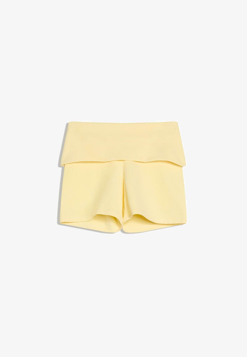 Shorts taille haute jaune clair avec une large ceinture repliée, posés à plat sur un fond blanc.