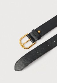 Juodas odinis diržas su tekstūruota paviršiaus danga, su auksiniu metaliniu sagtimi ir apskritu akcentu netoli sagties. Įvairios reguliavimo skylutės.