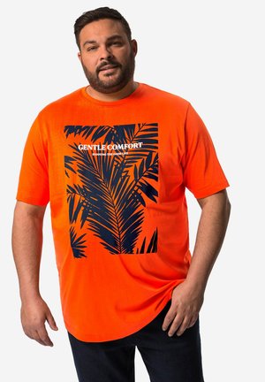 Camiseta de color naranja brillante hecha de una tela suave, con un gráfico de hoja de palma en color marino y el texto "CÓMODO Y SUTIL" en letras gruesas.