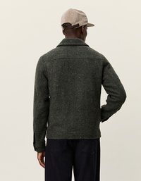 Zaļš zigzaga raksta žakets, izgatavots no struktūrēta auduma, ar platu apkakli un sānu kabatām. Aizmugures skats bez redzamām aizdares.