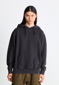Dark gray hoodie with a front pocket, drawstring hood, and ribbed cuffs. Features a subtle brand logo on the chest. Cotton blend fabric.