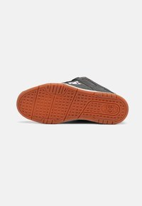Black and gray sneaker sole with a textured orange rubber tread, featuring geometric patterns and a logo near the heel.