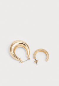 Goudkleurige oorbellen met een grote maanvormige ring en een kleinere opgerolde ring. Beide hebben een glanzende metallic afwerking en verschillende texturen.