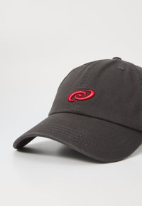 Svart bomullscaps med bøyd skjerm og rødt brodert logo. Har sømdetaljer på toppen og justerbar stropp bak.