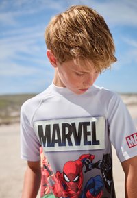 Hvid rashguard med korte ærmer med Marvel-logo og farverige grafik af Spider-Man og Black Panther, lavet af blødt, letvægtsstof.