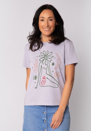 Hellblaues T-Shirt aus Baumwolle mit einer Linienzeichnung einer sitzenden Figur, die mit floralen und herzförmigen Akzenten in Grün und Rot verziert ist.