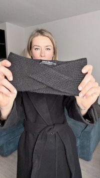 Bandeau en tricot noir avec un design torsadé, fabriqué à partir d'un tissu texturé. Étiquette de la marque visible au centre.