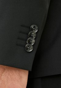 Manica di giacca nera con quattro bottoni rotondi neri e cuciture a contrasto. Tessuto liscio, vestibilità su misura.