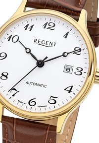 Goudkleurig automatische horloge met een witte wijzerplaat, zwarte Arabische cijfers en een bruine leren band met een krokodillenpatroon. Datumschaal op 3 uur.