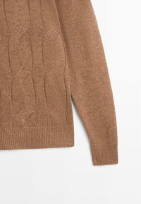 Brauner gestrickter Pullover mit Zopfmuster, strukturierter Stoff und gerippten Bündchen an Ärmeln und Saum. Der Schnitt ist locker und entspannt.