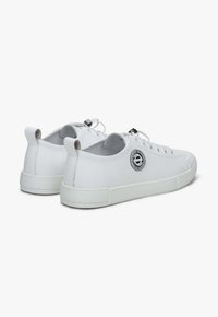 Białe sneakersy z gładkiej syntetycznej powierzchni, zaokrąglonym noskiem i gumową podeszwą. Posiadają naszywkę z logo po boku oraz sznurowaną konstrukcję.