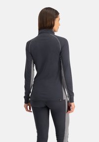 Donkergrijze trui met lange mouwen, een hoge kraag en contrasterende lichtgrijze zijpanelen; zachte stof en een getailleerd ontwerp.