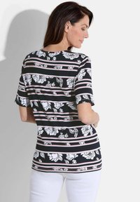 Zwart-wit bloemenblouse met horizontale roze en witte strepen. Korte mouwen, ronde halslijn en een losse pasvorm. Witte achtergrond.