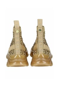 Baskets montantes beiges avec un motif texturé, des accents élastiques et une semelle en caoutchouc brillant. Présente des sangles de marque et des languettes de tirage au niveau du talon.