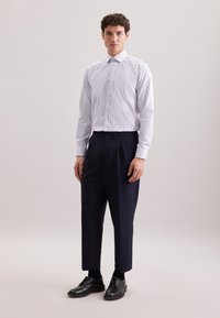 Camicia a maniche lunghe bianca e blu a righe abbinata a pantaloni pieghettati blu navy e scarpe da cerimonia nere; tessuto morbido, vestibilità su misura.
