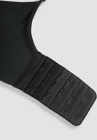 Sostén negro con una tela suave, que presenta una banda ancha ajustable con múltiples cierres de gancho y ojal para personalizar el ajuste.