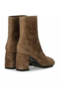 Stivaletti alla caviglia in suede marrone con tacco a blocco, caratterizzati da una texture liscia e una punta arrotondata. La suola presenta un leggero motivo di presa per una migliore aderenza.