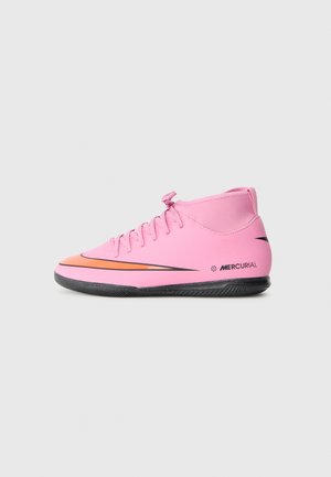 Bottine de foot Nike Mercurial rose avec un swoosh orange et noir sur fond blanc, vue de côté.