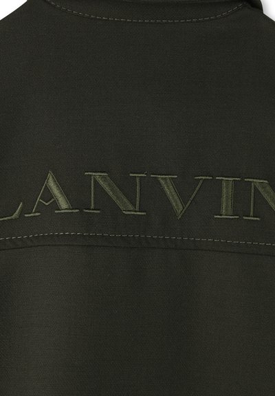 Donkergroene stof met geborduurde "LANVIN" tekst in bijpassend groene draad over de bovenrug, met zichtbare stiksel.