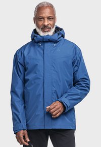 Blaue wasserdichte Jacke mit einer enganliegenden Kapuze, vorderem Reißverschluss und verstellbaren Manschetten. Sie hat eine glatte Textur und minimale Markenkennzeichnung.