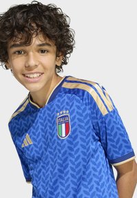 Blå fotbollströja med ett lövmönster, guldaccents och en Italia-märke på bröstet. Kortärmad med rund halsringning.