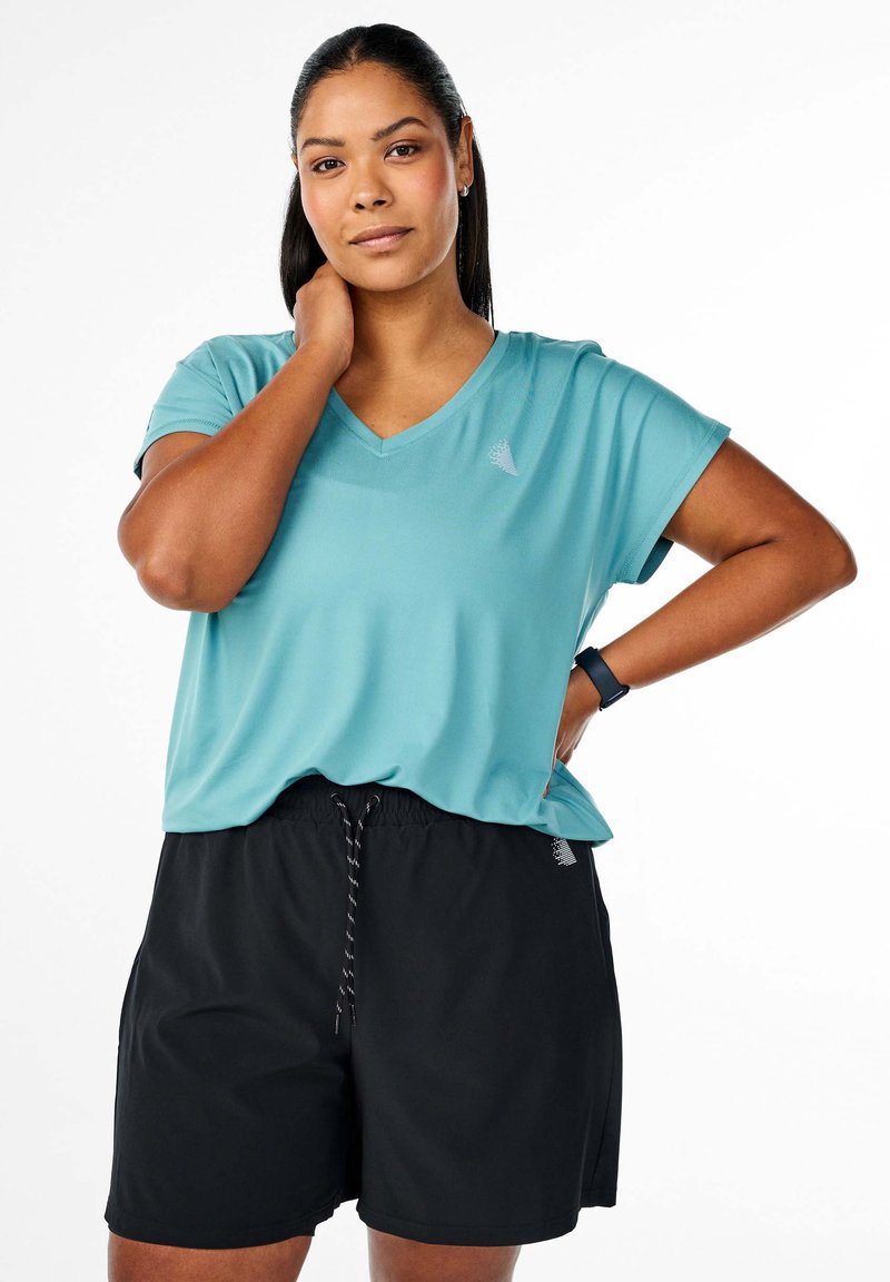 V-kauluksellinen turkoosi t-paita kevyestä kankaasta yhdistettynä mustiin shortsia, joissa on elastinen vyötärö ja kiristysnauha.