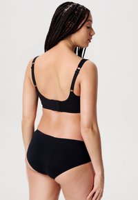 Czarny stanik z regulowanymi ramiączkami i zapięciem na haftkę. Posiada gładką, matową fakturę. W komplecie z dopasowanymi czarnymi bezszwowymi majtkami.