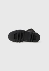 Suola nera da stivale con superficie di grip texture, caratterizzata da scanalature orizzontali e punta arrotondata, realizzata in materiale gommoso.