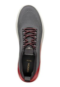 Sneaker tessile grigio con tomaia in rete, dettagli rossi, lacci neri e suola in gomma bianca. Presenta una linguetta imbottita e un logo sulla soletta.