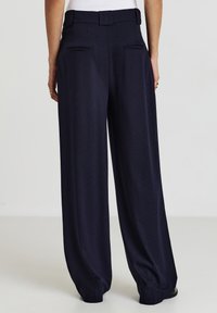 Weite marineblaue Hosen mit gerippter Textur, einem taillierten Gürtel und Gesäßtaschen, entworfen für eine lockere Passform.