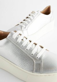 Silver textured leather sneakers with white laces and a white rubber sole. Features a low-top design and flat, round toe.